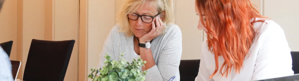 Två kvinnor som sitter vid ett bord och pratar