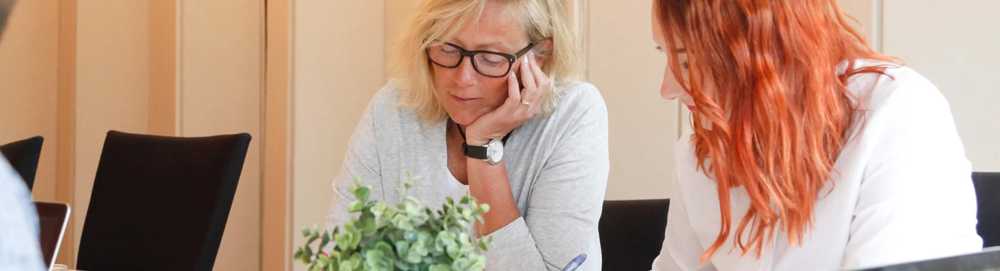 Två kvinnor som sitter vid ett bord och pratar