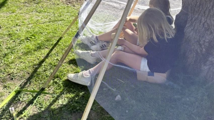 Två barn sitter och leker i en koja