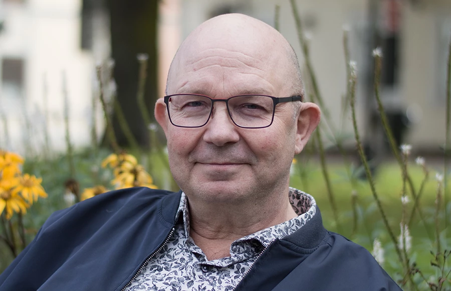 En man med glasögon och blå jacka