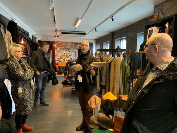 Jonas visar upp en kashmirhalsduk av spillmaterial f&ouml;r kommundirekt&ouml;r Marita, kommunstyrelsens ordf&ouml;rande Mats och vice kommunstyrelsens ordf&ouml;rande Hans.