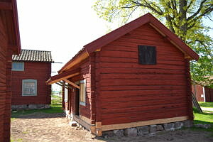 Bilden visar en gammal rödmålad byggnad på Stora Skedvi hembygdsgård