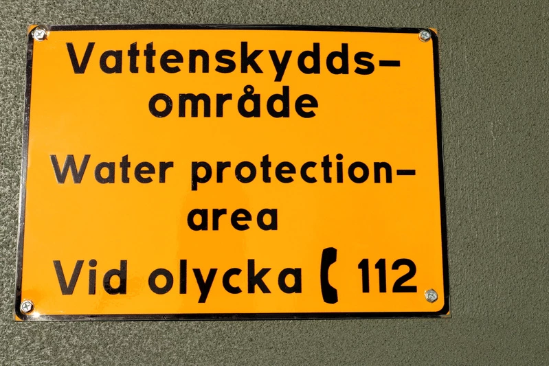 Skylt som ger information om var man ska ringa vid en olycka vid vattenskyddsområde.