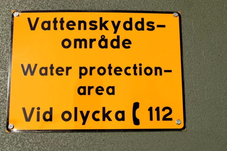 Skylt som ger information om var man ska ringa vid en olycka vid vattenskyddsområde.