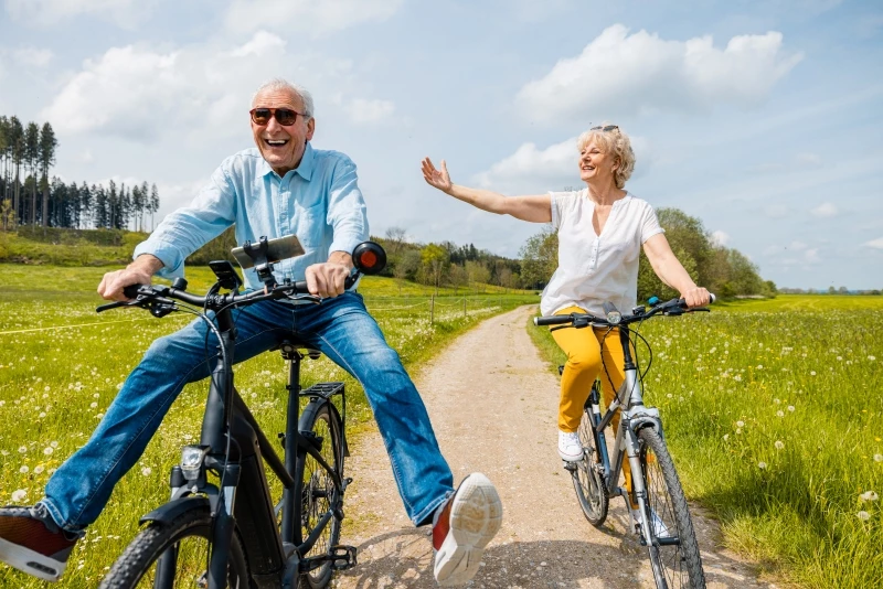 Två glada pensionärer på varsin cykel