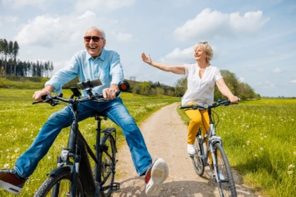 Två glada pensionärer på varsin cykel