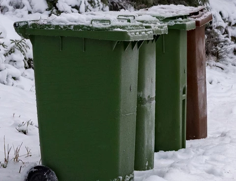 Flera soptunnor vid en vinterväg.