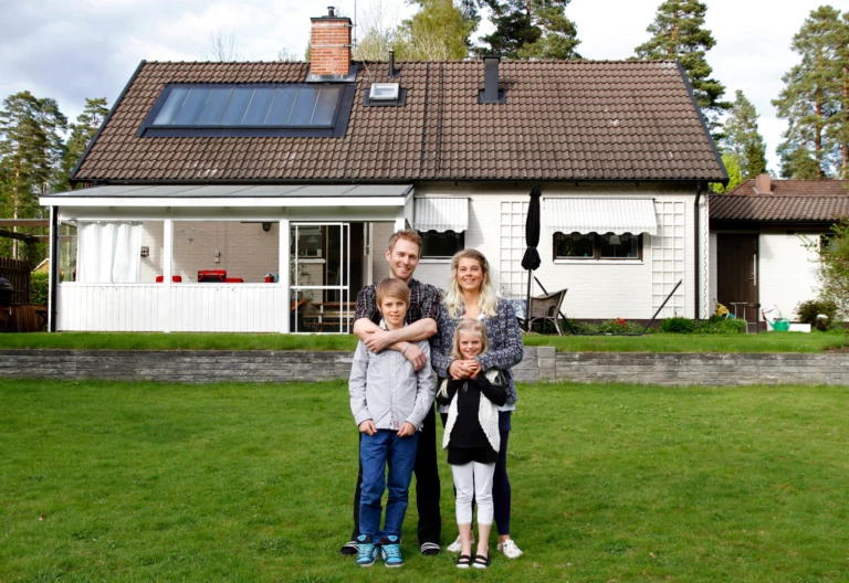 En familj står framför ett hus.