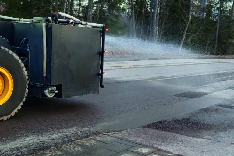 En sopmaskin på vägen som sprutar vatten