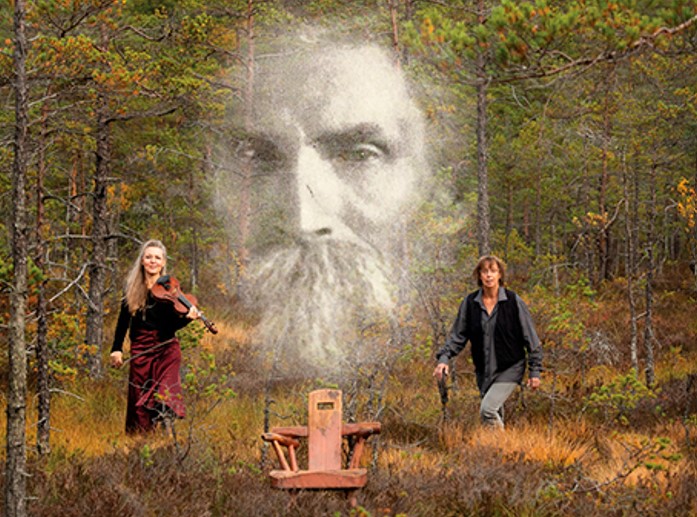 En fantasifull bild på två musiker i en skog. de håller i sina instrument och i samma bild syns ett stort ansikte av en man med skägg. ansiktet är transparent och svartvitt som på ett gammalt foto och är skapt som en extra effekt, som för att påminna och svunna tider och människor