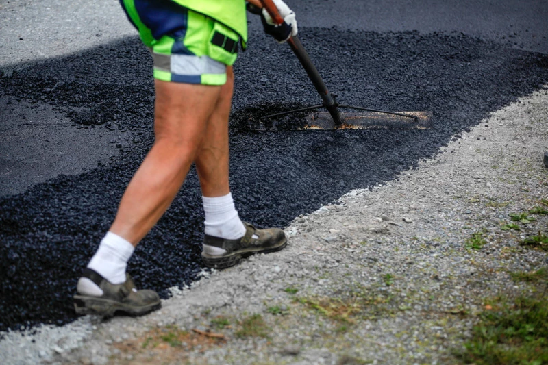 Asfaltering pågår. Person som rakar ut asfalt.