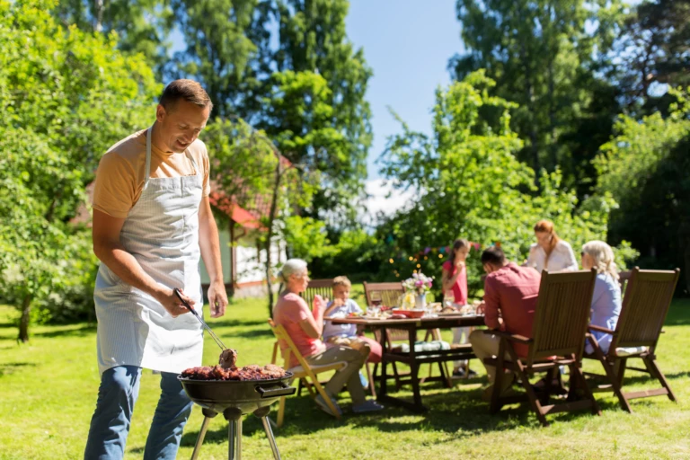 Man som grillar i trädgården