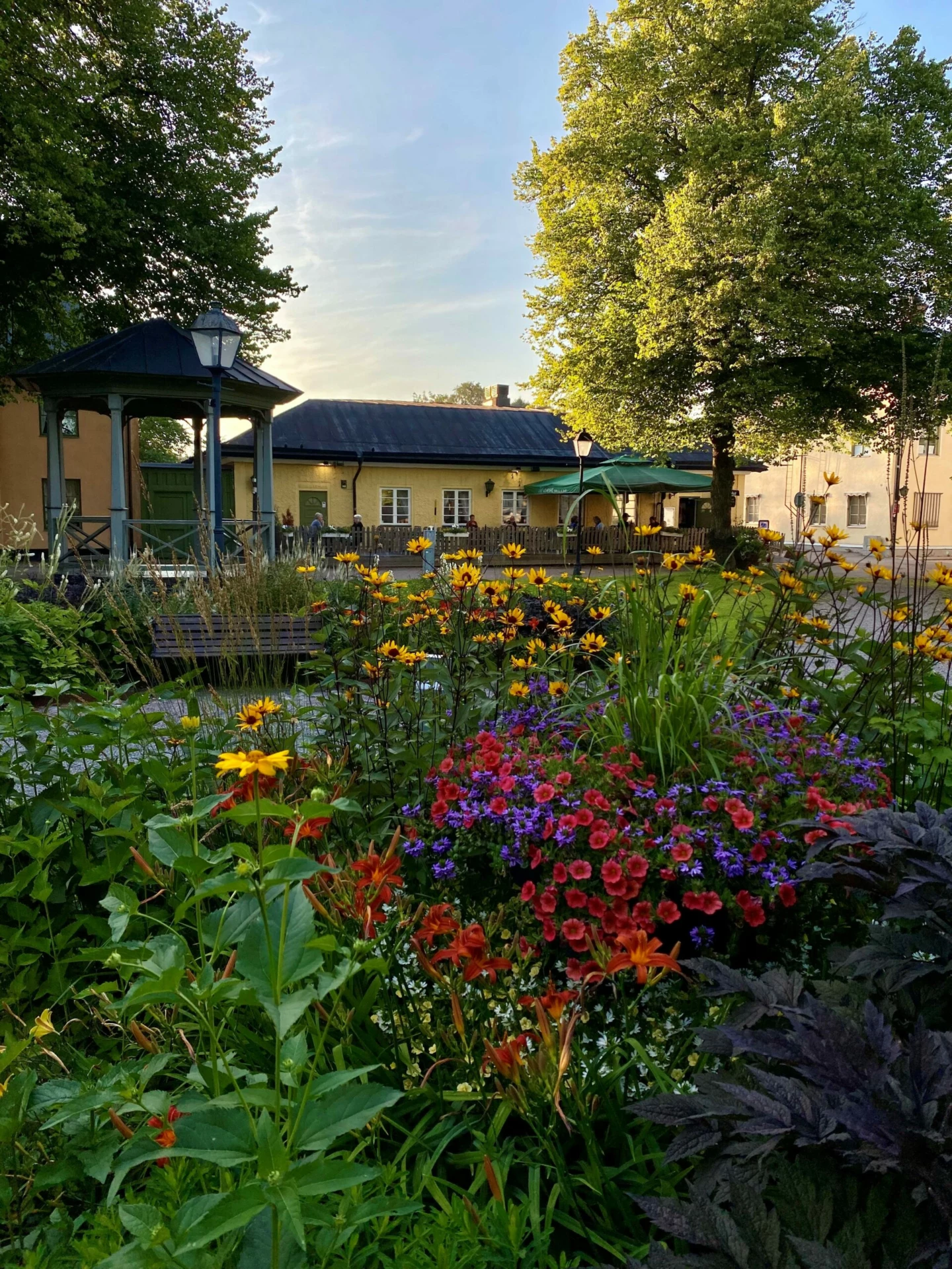 Rådhustorget i Säter med färgglada blommor i rabatterna och uteservering i bakgrunden