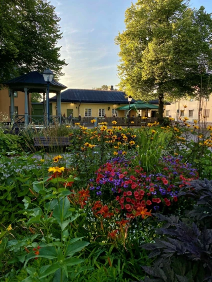 Rådhustorget i Säter med färgglada blommor i rabatterna och uteservering i bakgrunden