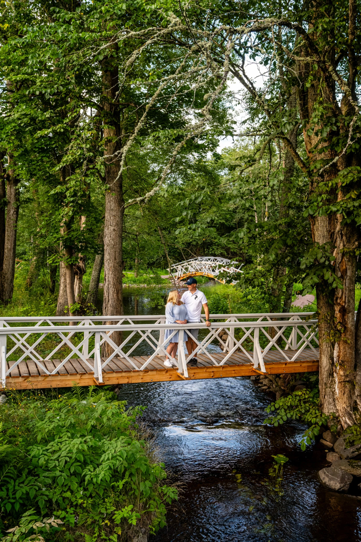 en kvinna och en man håller om varandra på en bro i engelska parken i grängshammar