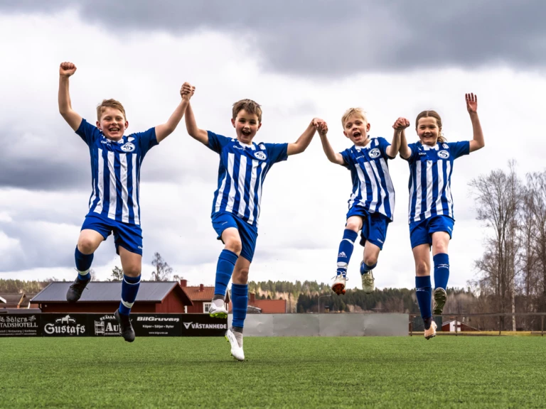 Fyra fotbollsspelare hoppar hand i hand upp i luften