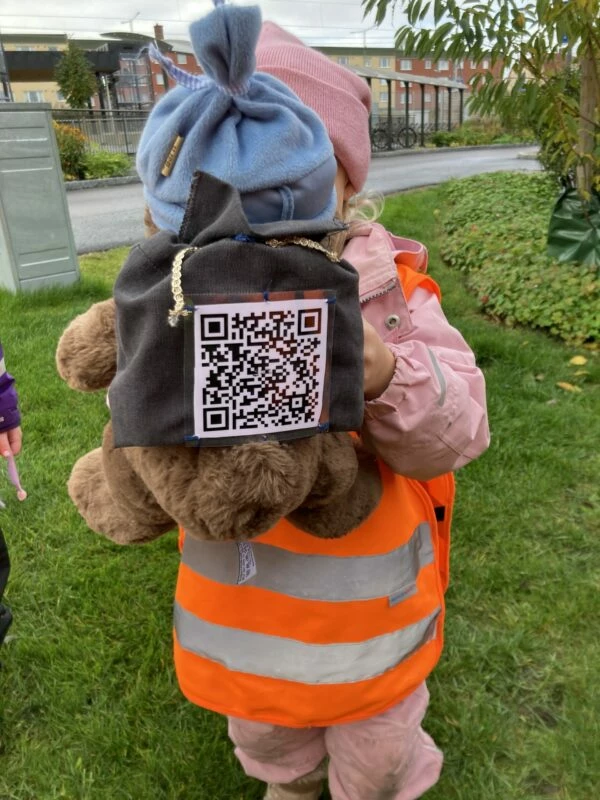 Bjarne sitter på ryggen av ett barn, med sin qr-kod.