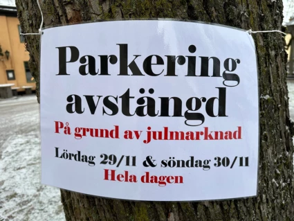 Skylt som sitter på ett träd och där det står att parkeringen är avstängd 29 och 30 november på grund av julmarknaden