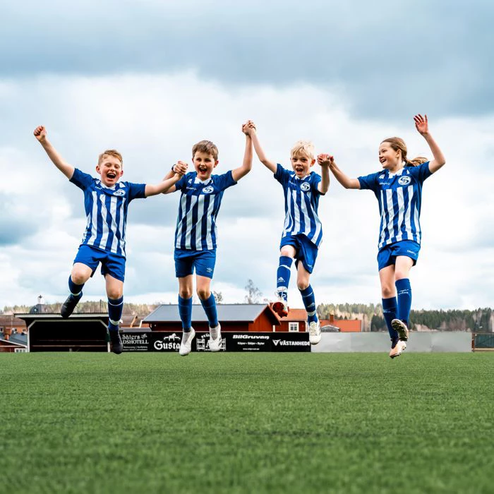 Fyra barn håller varandra i handen och hoppar