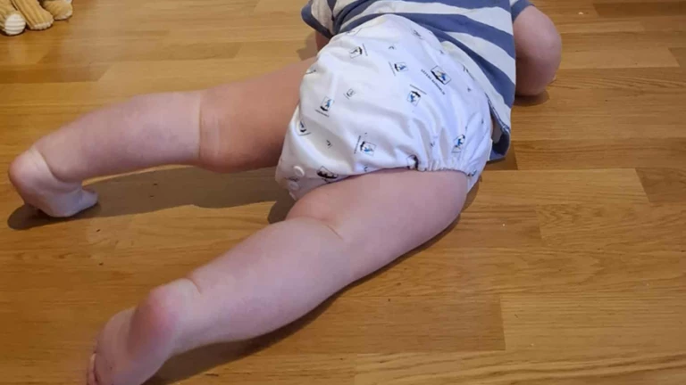 Tygblöja på litet barn som kryper på golvet