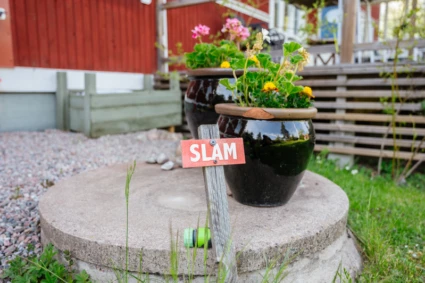 Cementbrunn med två blomkrukor ovanpå
