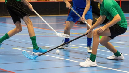 Tre personer spelar innebandy i en idrottshall