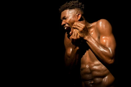 Ett foto på en man på en scen. bakgrunden är helt svart. han har en kraftfullt utryck i sitt ansikte, som av smärta.