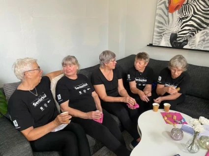 Fyra kvinnor sitter och fikar i en soffa