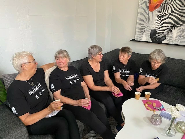 Fyra kvinnor sitter och fikar i en soffa