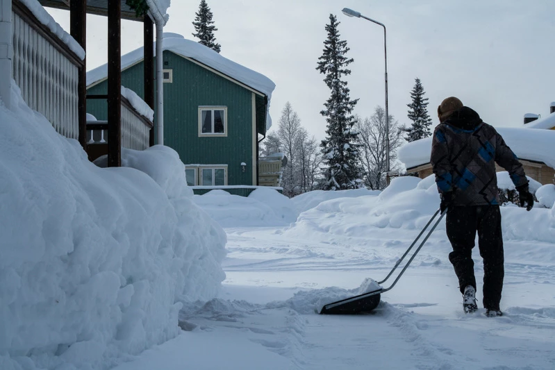 en person som skottar snö på sin uppfart