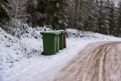 flera soptunnor som står efter en vinterväg
