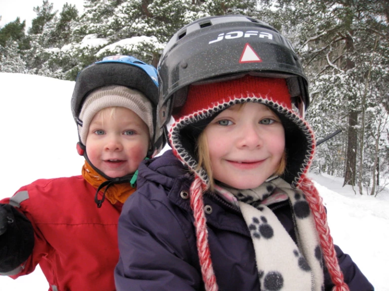 två barn som åker pulka och är glada