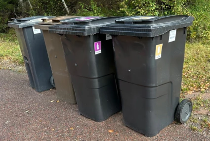 fyra soptunnor på en rad längs en väg en höstdag