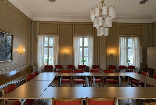 Sammanträdesrummet fullmäktigesalen med bord och stolar.