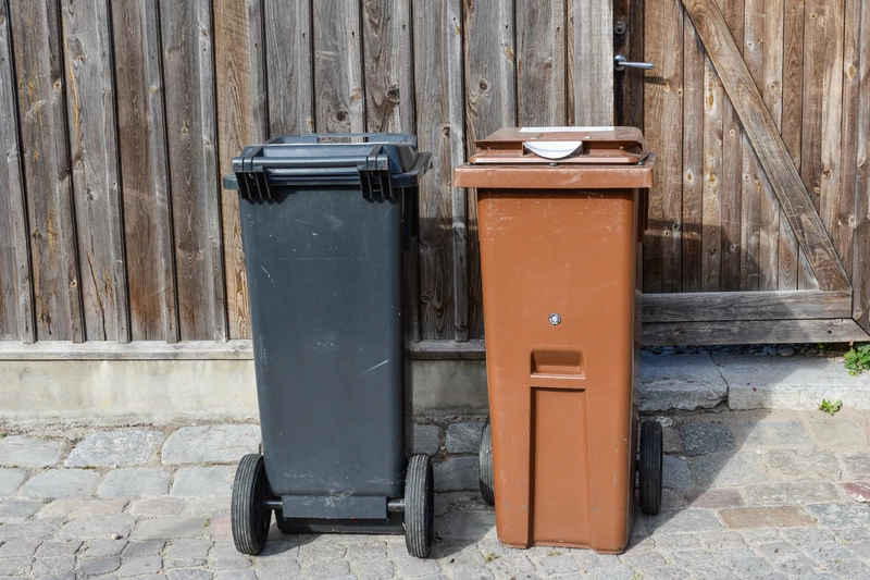 två soptunnor står mot en vägg