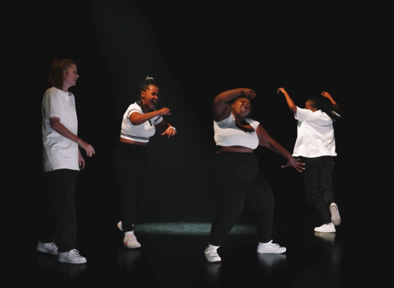Scenisk bild från dansföreställningen Groove. 4 tjejer poserar i olika streetdans-positioner