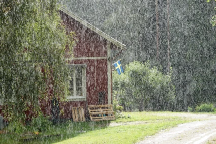 en röd stuga där det regnar ett sommarregn över