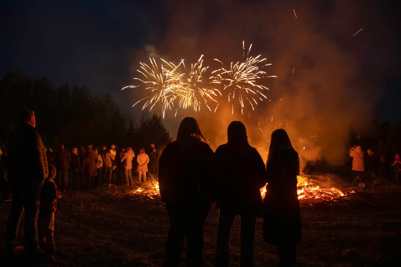En valborgsmässoeld med fyrverkerier i bakgrunden
