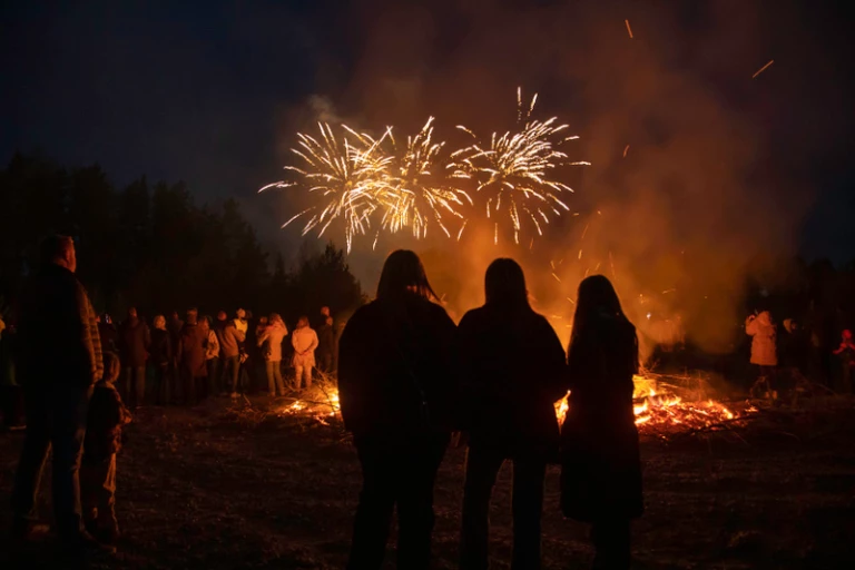 En valborgsmässoeld med fyrverkerier i bakgrunden