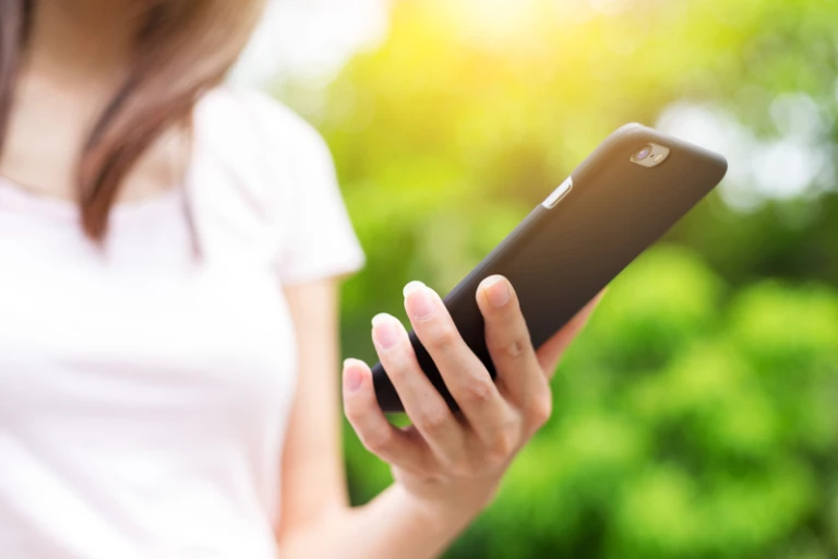 en kvinnan håller i en mobiltelefon