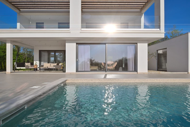 Pool i trädgård vid villahus med altan och utemiljö