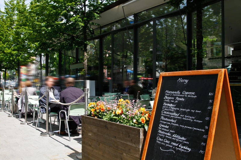 en uteservering med bord, stolar och några blommor