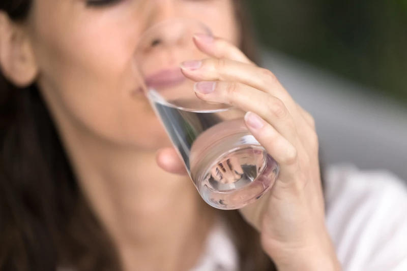 Kvinna dricker ur ett glas med vatten.
