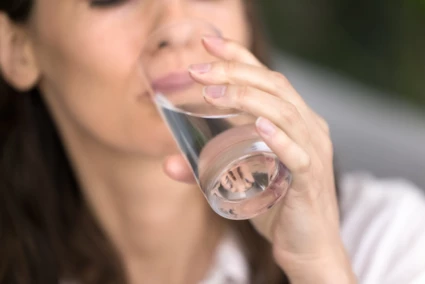 Kvinna dricker ur ett glas med vatten.