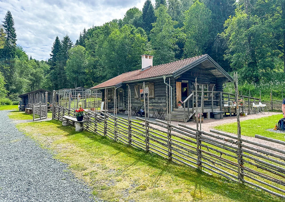 en grå fäbod med en gärdesgård framför