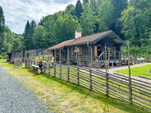 en grå fäbod med en gärdesgård framför