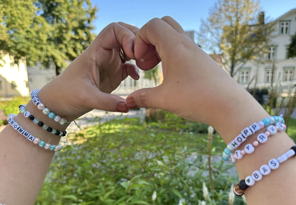 Två händer som hålls ihop som ett hjärta med armband på handlederna.