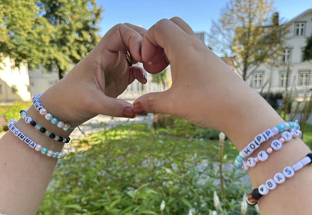 Två händer som hålls ihop som ett hjärta med armband på handlederna.