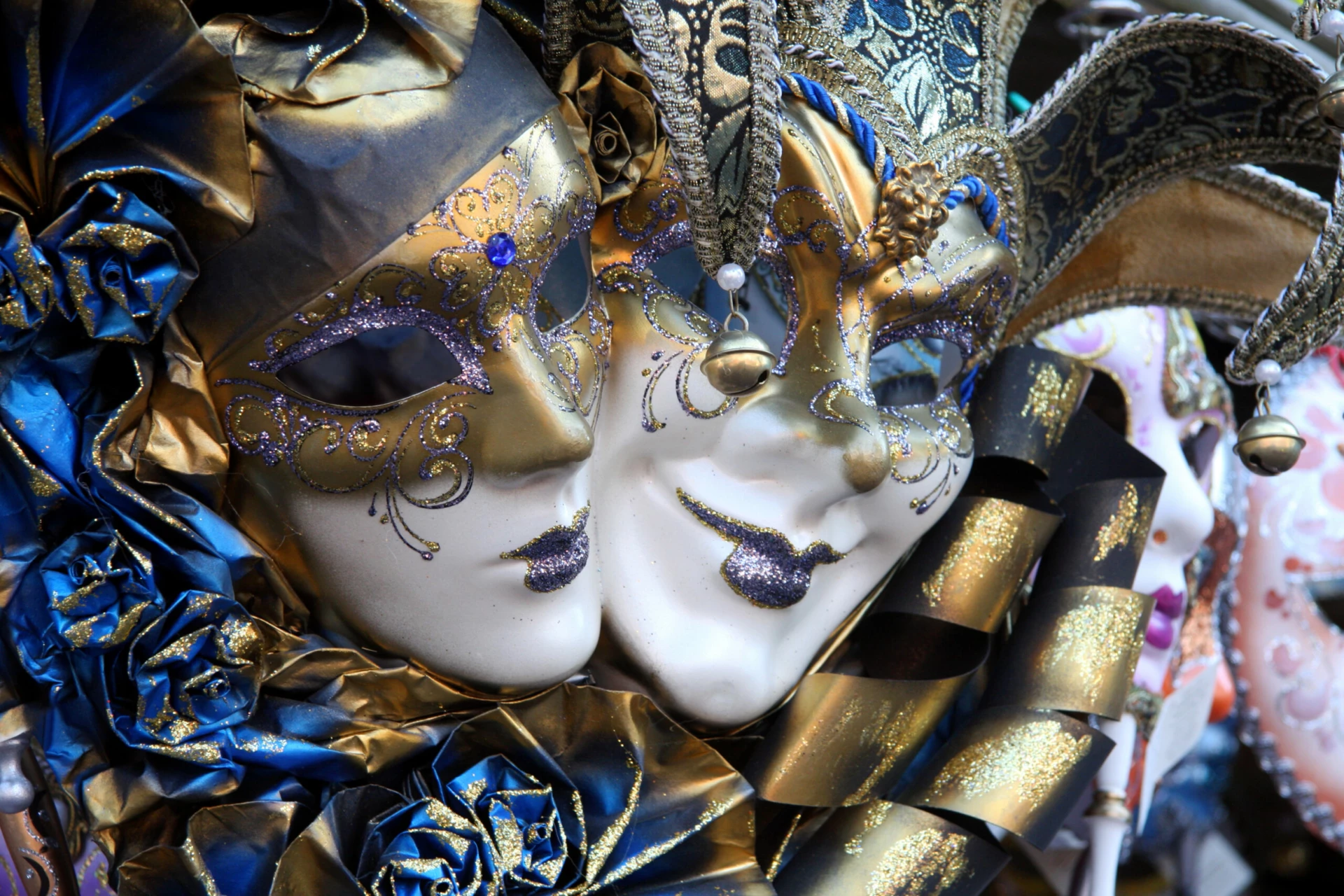 En bild på två venetianska masker, en slags maskeradmasker. De är utsmyckade i blått och guld
