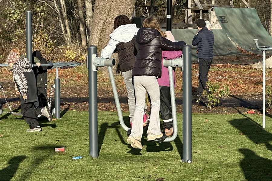 Besökare tränar på utegymmets redskap i Pep Park Säter, med träd och grönska i bakgrunden.